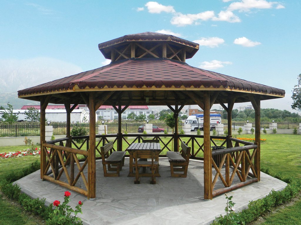 Hexagonal wooden gazebo with table and benches in a park
