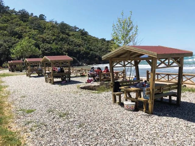 Wooden gazebos and picnic units on a pebble beach